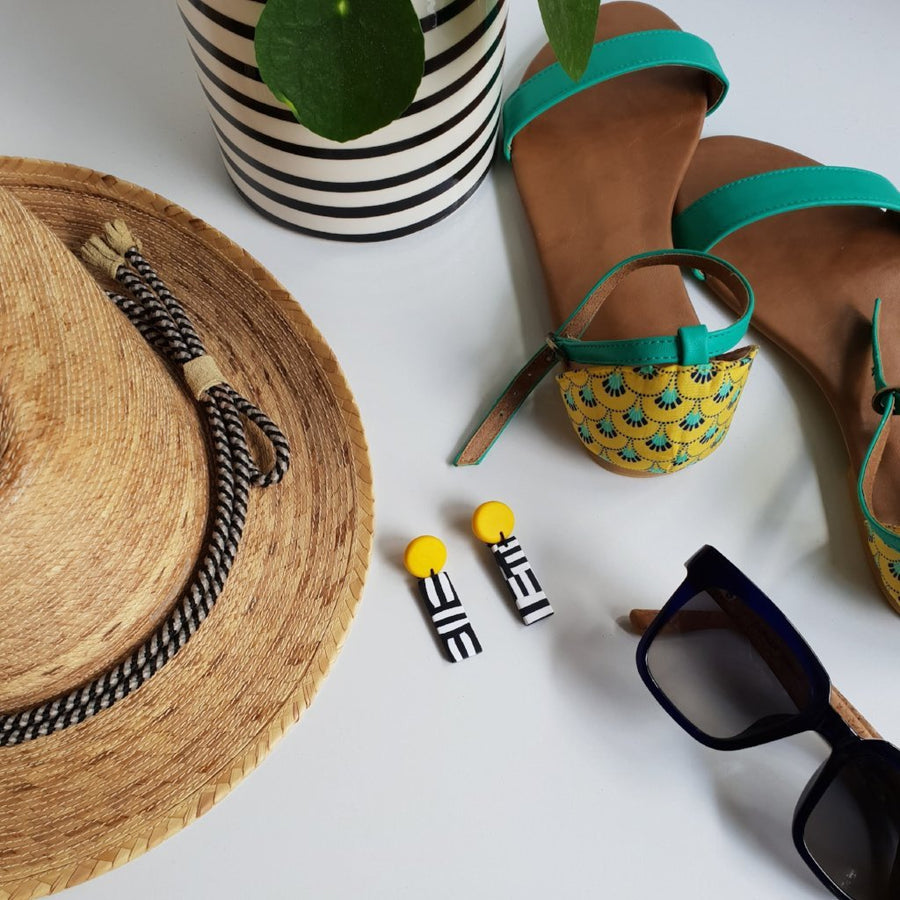 A lifestyle photo with a hat and plant, a pair of shoes plus yellow Party Dangles - Clac Clac Design